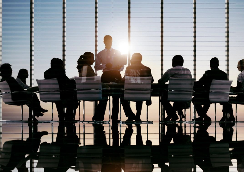 A group of people sitting at a table in front of a window.