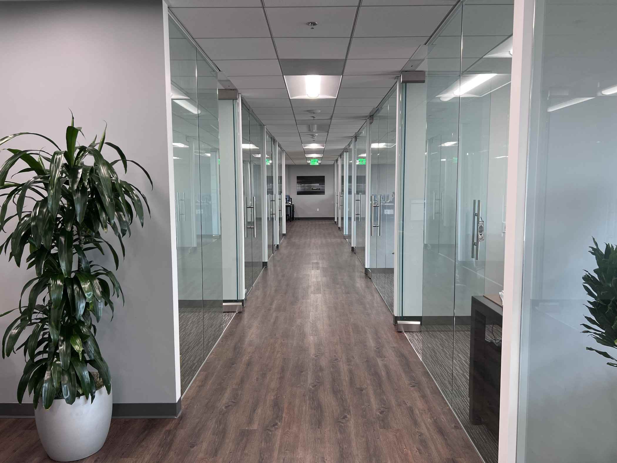 A hallway with glass walls and wooden floors.