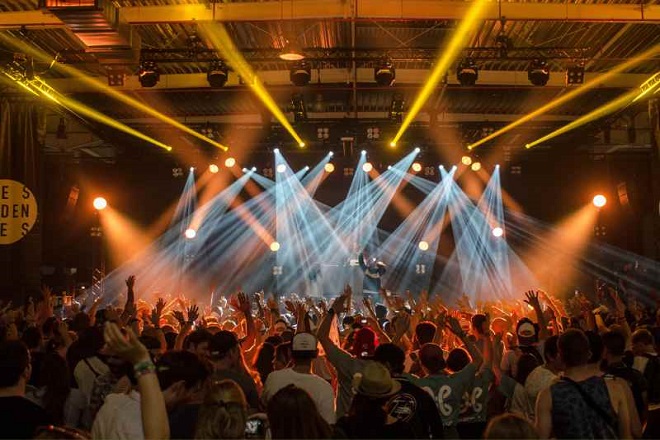 A crowd of people in front of lights on a stage.