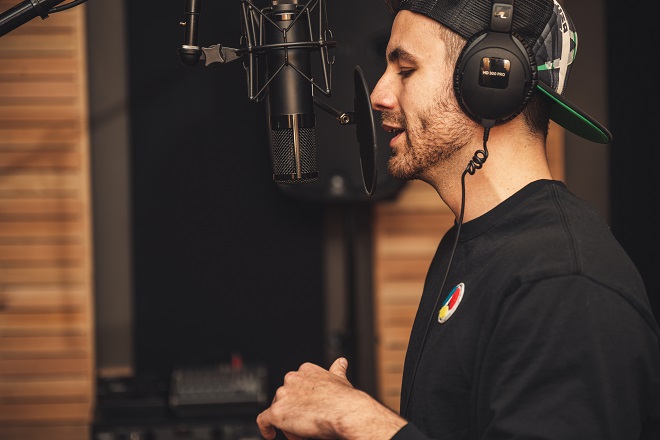 A man with headphones on singing in front of a microphone.