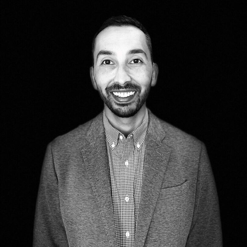 A man in a suit and tie smiling for the camera.