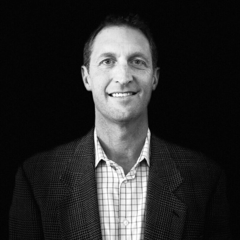 A man in a suit and tie smiling for the camera.